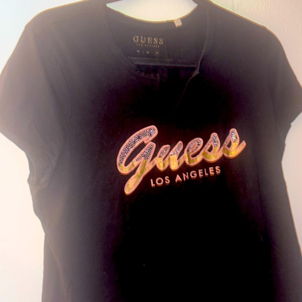 T-shirt features a script logo design in lettering embellished with rhinestones.